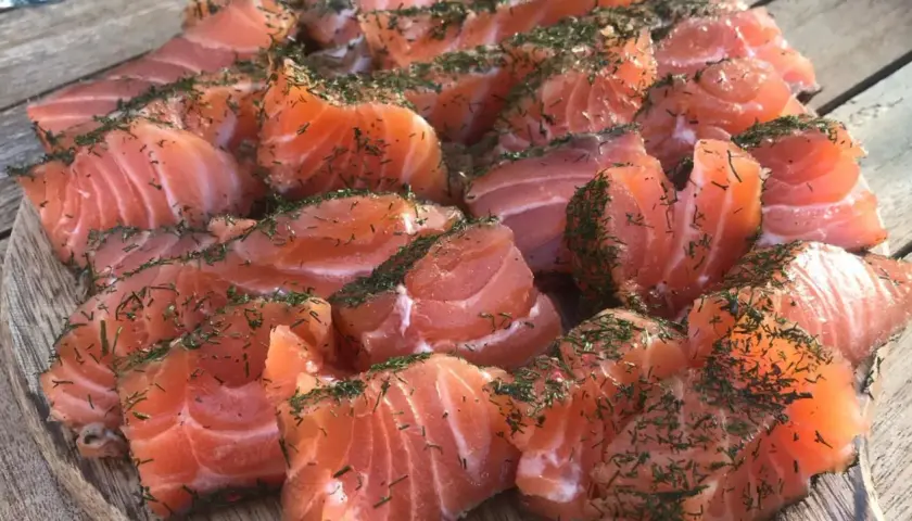 Des morceaux de saumon gravlax, parsemés d'aneth, prêts à être dégustés. Quel vin avec saumon gravlax ? Un blanc sec ou un rosé léger serait parfait.