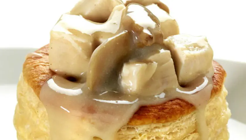 Une bouchée à la reine poulet, garnie de morceaux de volaille et d'une sauce crémeuse aux champignons, sur une pâte feuilletée dorée.