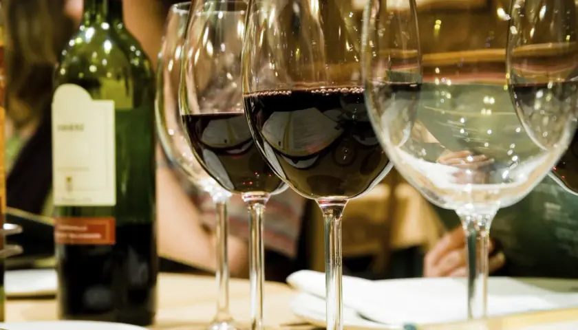 Bouteille de vin vert et verres remplis, révélant la belle couleur du vin rouge profond.