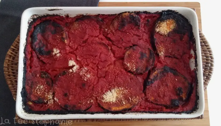 Un plat de parmigiana di melanzane tout juste sorti du four, avec des bords légèrement caramélisés et une sauce tomate savoureuse.
