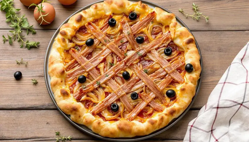 Pissaladière garnie d'oignons, d'olives et de lardons sur une pâte brisée ou feuilletée, prête à être dégustée.