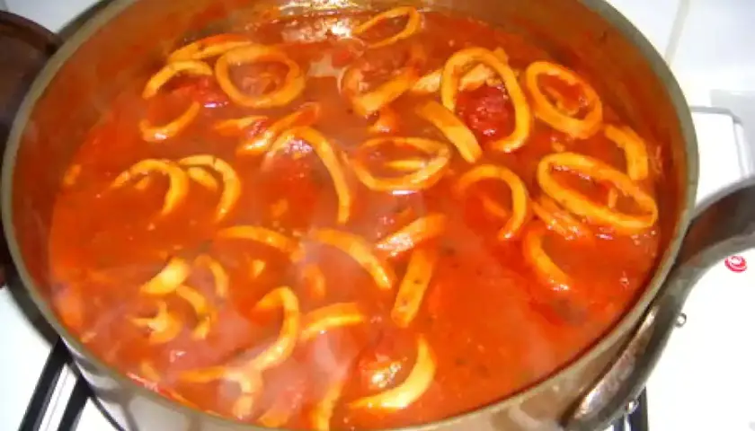Calamars à l'armoricaine mijotant dans une sauce tomate savoureuse. Un plat réconfortant prêt à être dégusté.