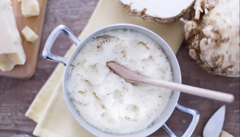 Un crémeux **purée de céleri** dans une casserole, avec du céleri-rave, du parmesan et du poivre.