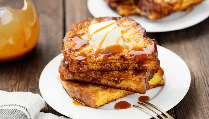 Pile de pain perdu doré, nappé de sirop et garni de beurre fondant. Un délice matinal.