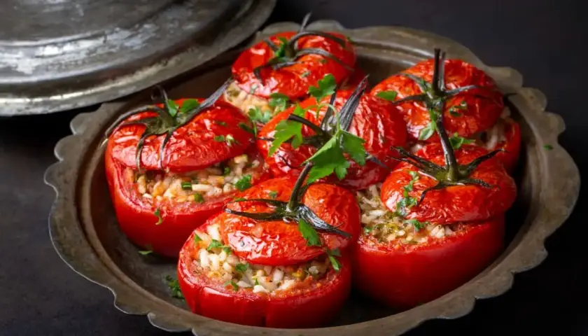 Tomates farcies au riz, garnies de persil frais, servies dans un plat en métal vieilli. Un délice simple et savoureux.