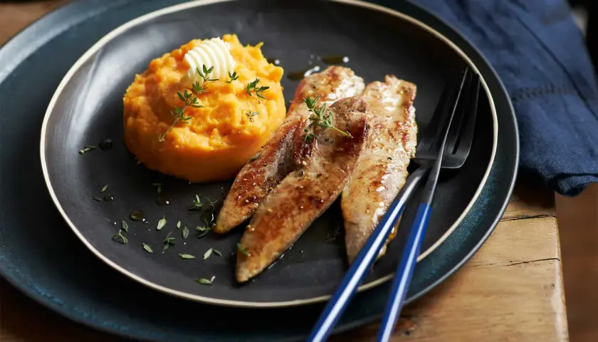 Trois aiguillettes de canard poêlées, servies avec une purée de patate douce onctueuse, garnie de thym frais et d'une noix de beurre.