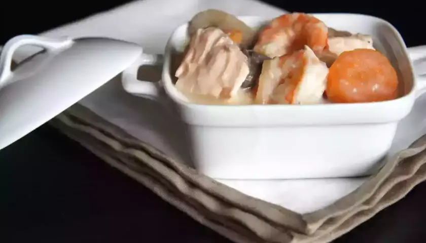 Blanquette de saumon et crevettes, nappée d'une sauce onctueuse au vin blanc, servie dans un ramequin blanc.