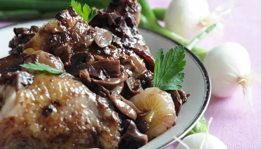 Coq au vin savoureux, garni de champignons et d'oignons. Parfait pour savoir que boire avec un coq au vin.