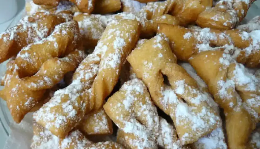 Une assiette généreuse de bugnes lyonnaises dorées, saupoudrées de sucre glace. La meilleure recette de bugnes lyonnaises pour un goûter gourmand.