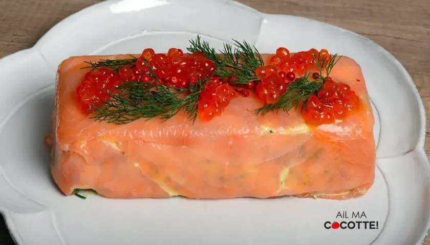 Terrine de saumon chef étoilé, ornée de perles de corail et d'aneth, une création culinaire raffinée.