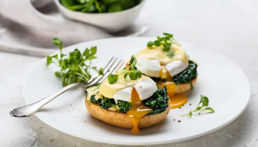 Deux œufs pochés sur des muffins anglais, recouverts de sauce hollandaise et d'épinards. Un déliceux œuf florentin prêt à être dégusté.