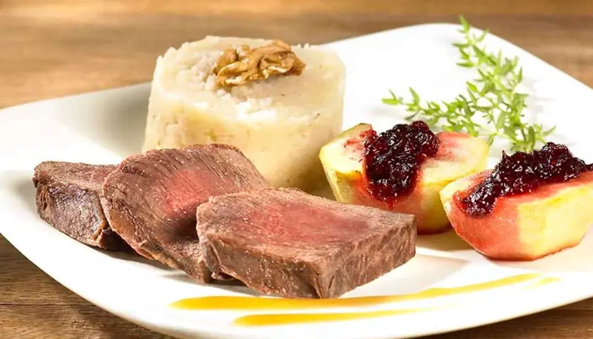 Tranches de fondue de biche, purée de céleri-rave à la noix, quartiers de pêche poêlée au coulis de fruits rouges.