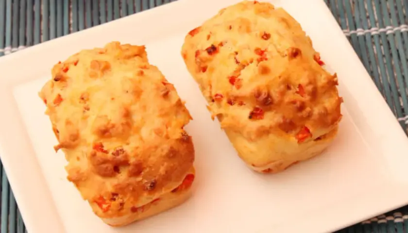 Deux petits pains dorés, un délicieux cake aux légumes, sont servis sur une assiette blanche.