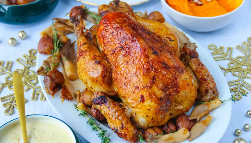 Un chapon rôti, doré et savoureux, servi avec des champignons et des marrons. Un plat festif parfait pour un repas de fête.