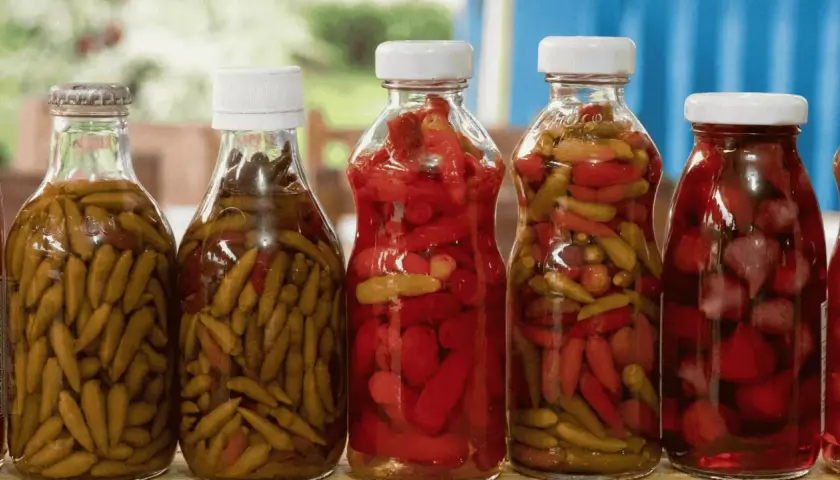 Bouteilles de piments verts et rouges marinés, prêts pour une recette de pickles maison.