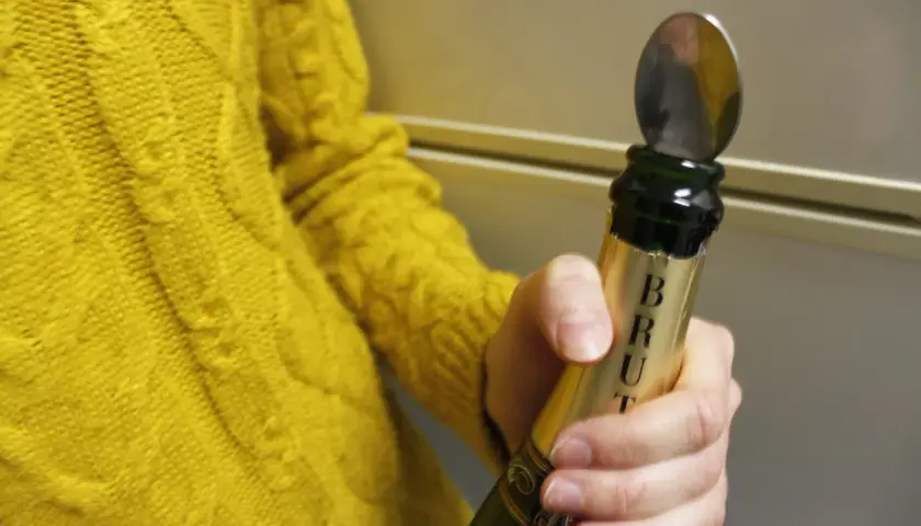 Une cuillère est insérée dans le goulot d'une bouteille de champagne pour montrer comment refermer une bouteille de champagne.
