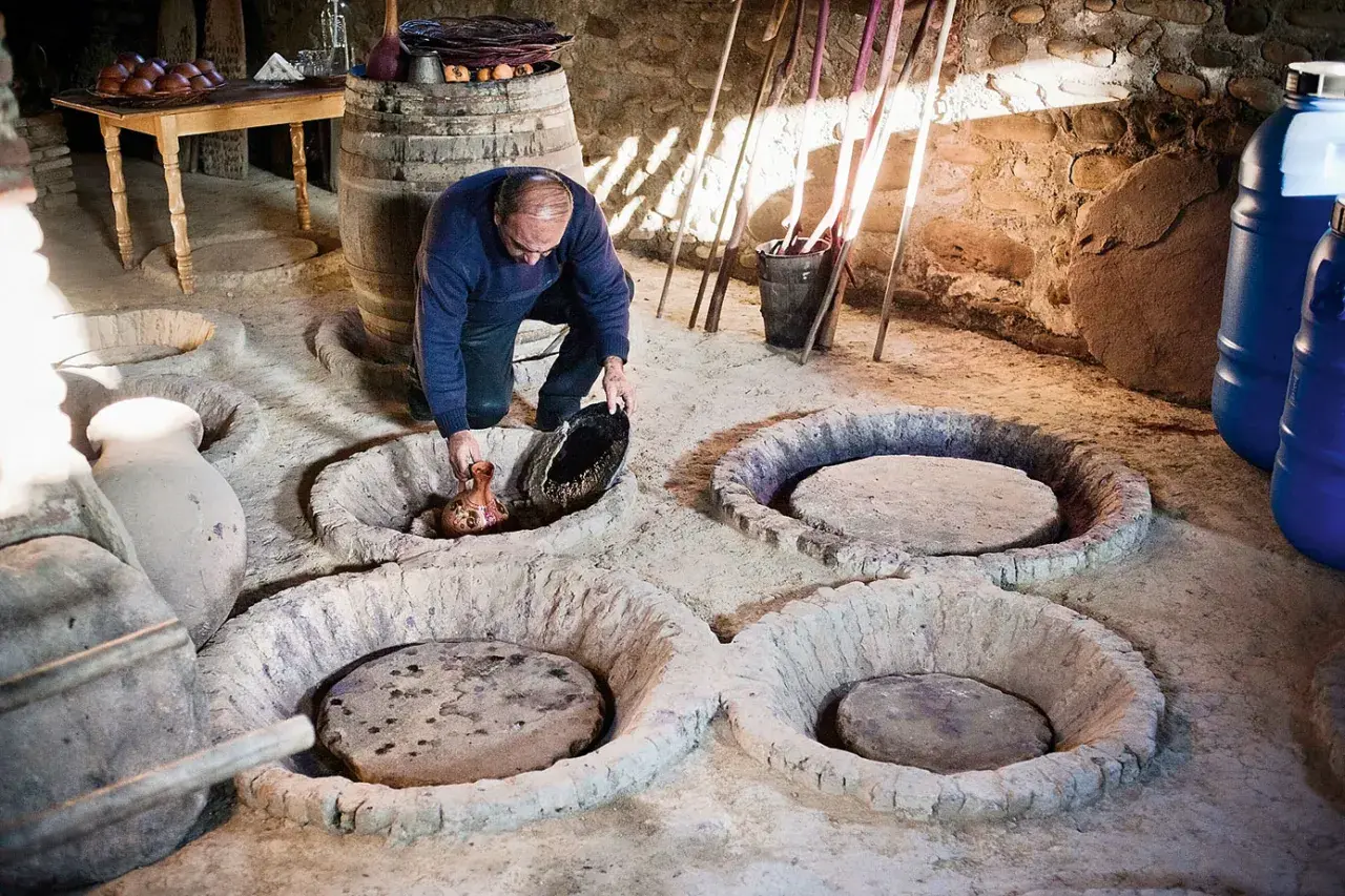 Un homme verse du jus de raisin dans une cuve en terre, peut-être pour recréer la méthode ancestrale qui a inventé le vin.