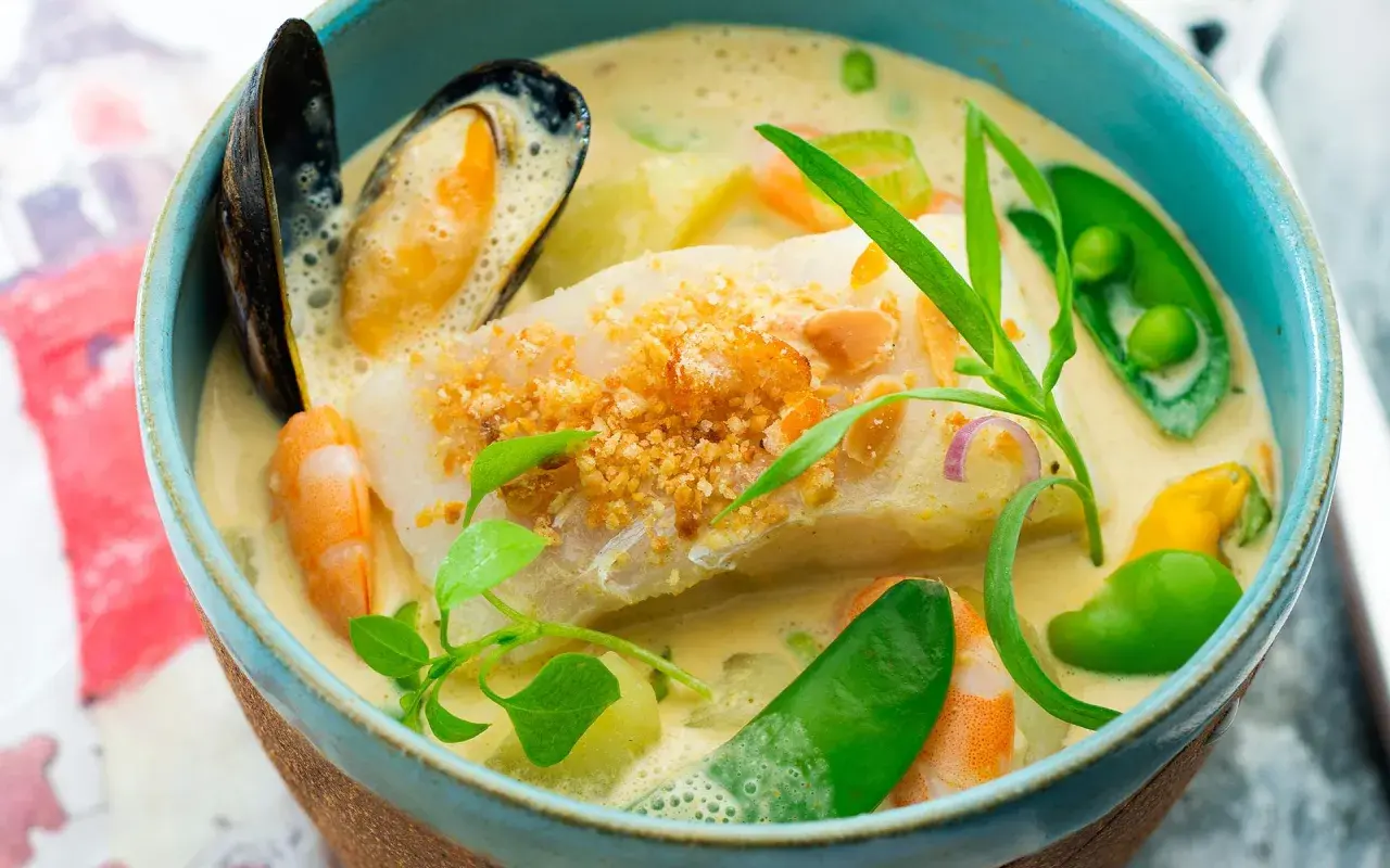 Une délicieuse marmite du pêcheur crémeuse avec poisson blanc, crevettes, moules, petits pois et herbes fraîches.