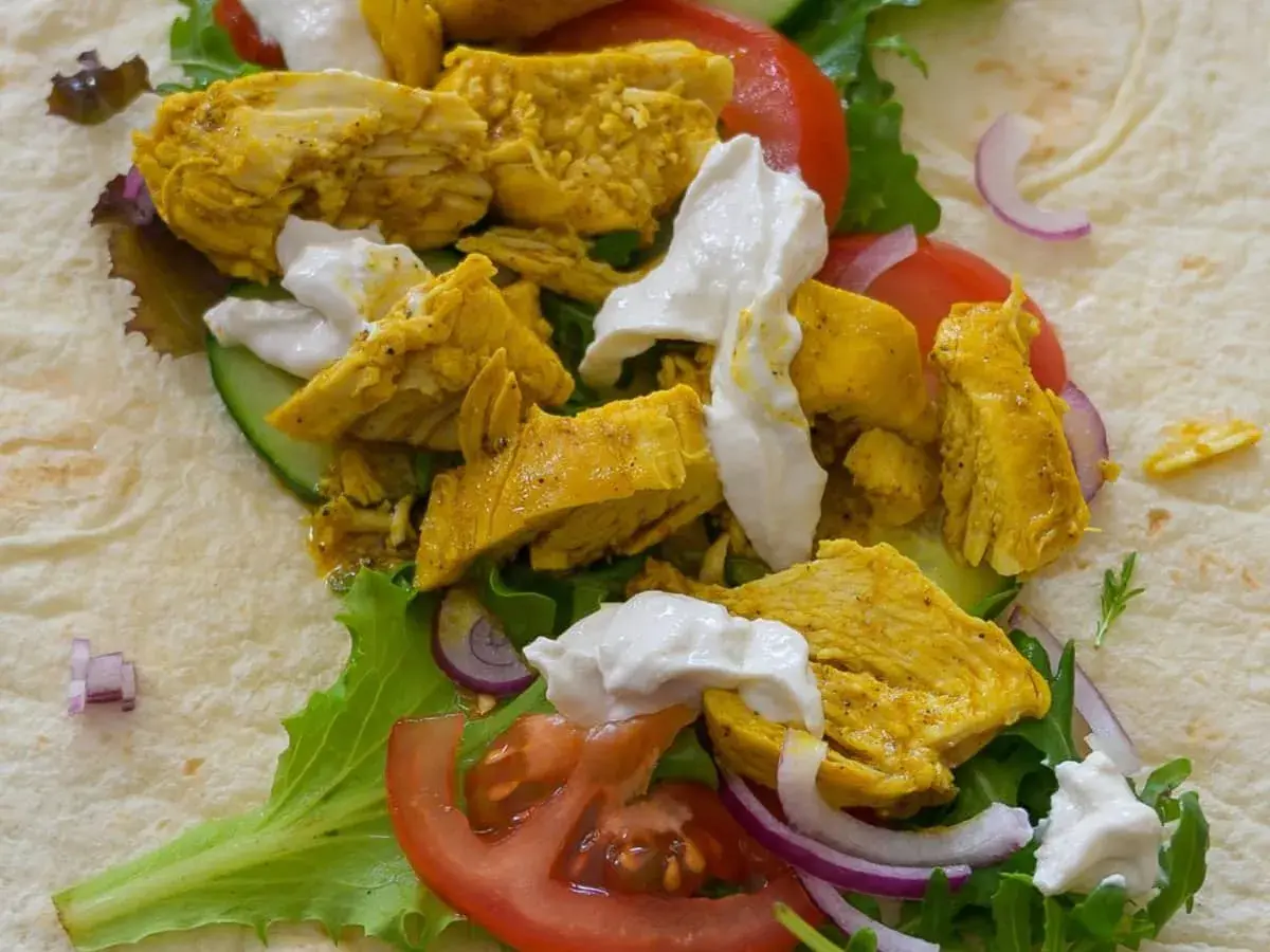Un délicieux chawarma poulet garni de légumes frais et de sauce blanche crémeuse, prêt à être dégusté.