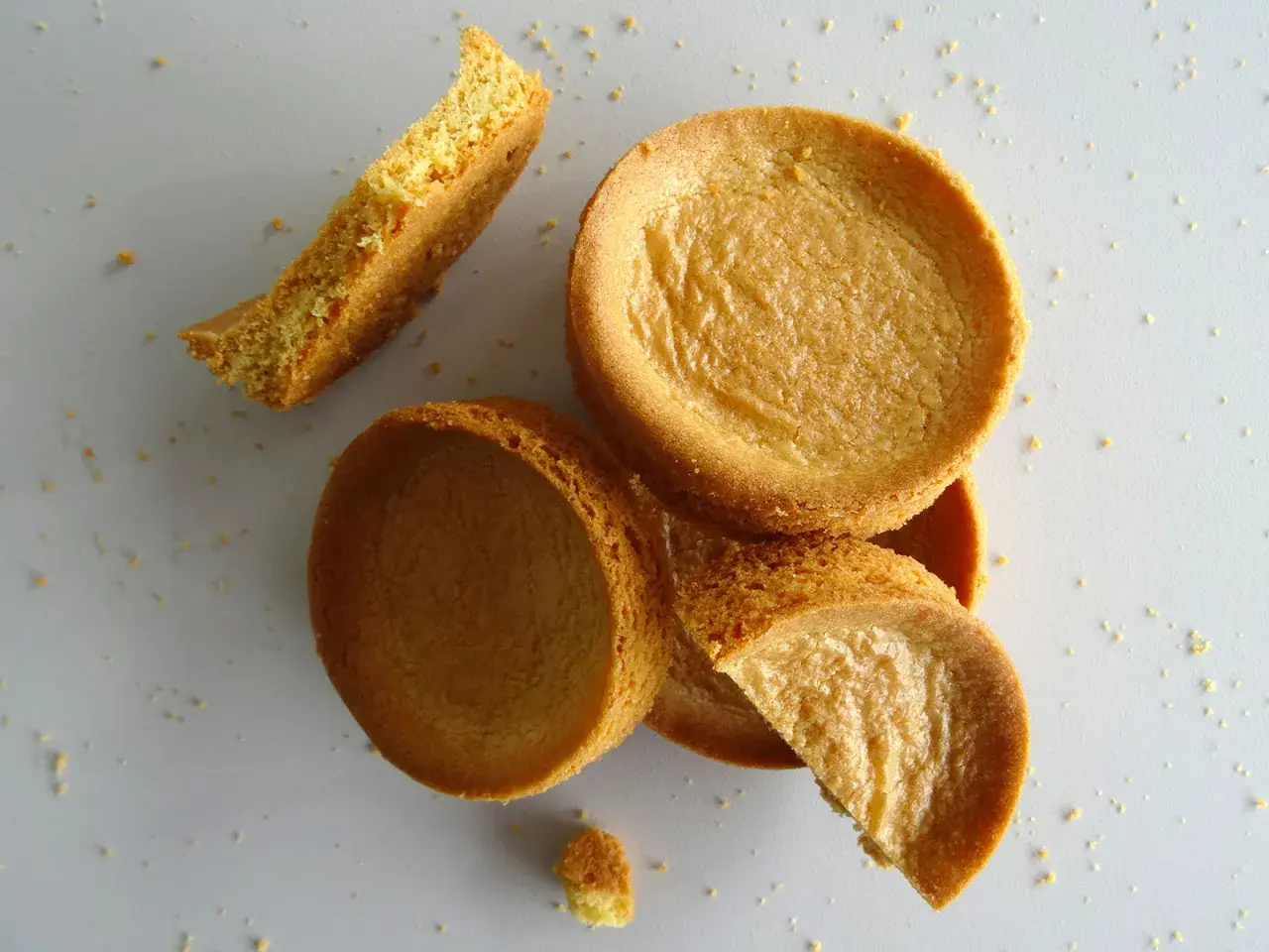 Des biscuits sablés bretons éparpillés, certains entiers, d'autres brisés, sur un fond clair.