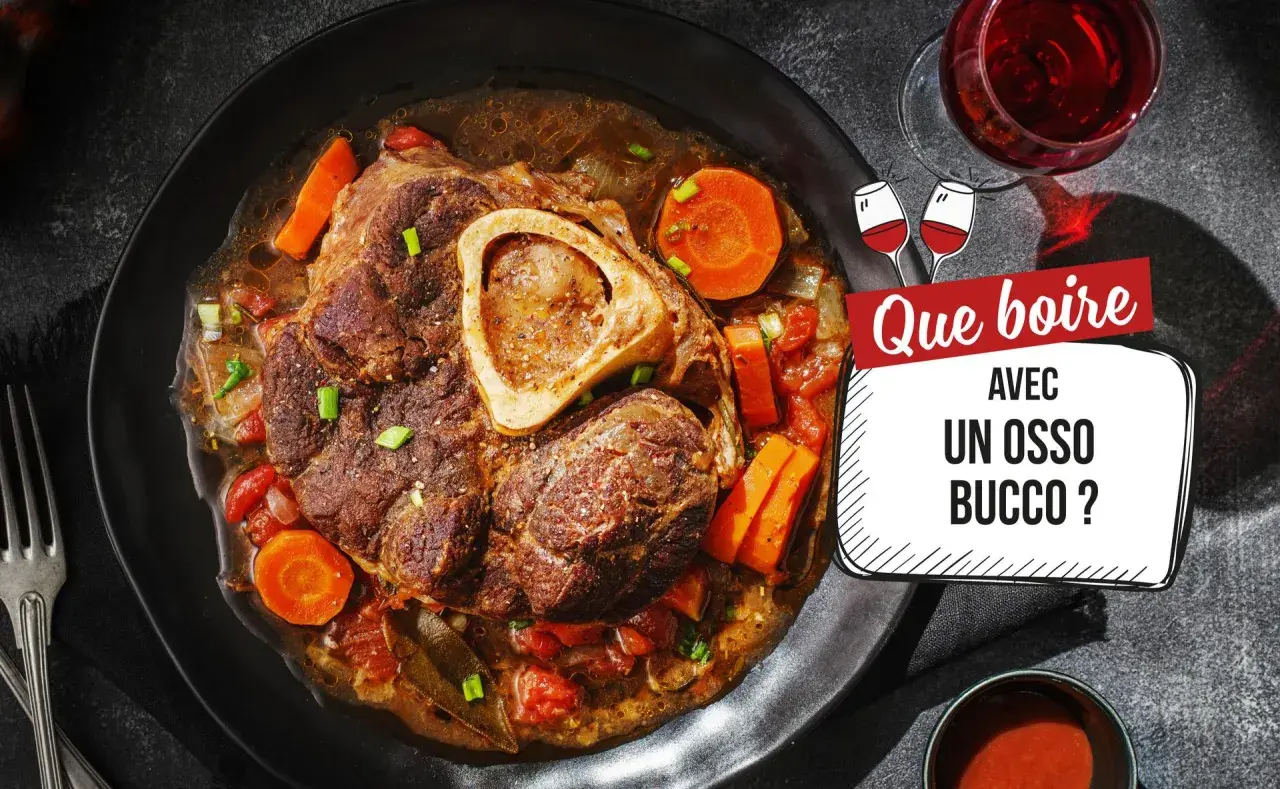Un plat d'osso bucco savoureux, avec carottes et tomates, servi dans une assiette noire. La question "Que boire avec un osso bucco ?" est affichée à côté d'un verre de vin rouge.