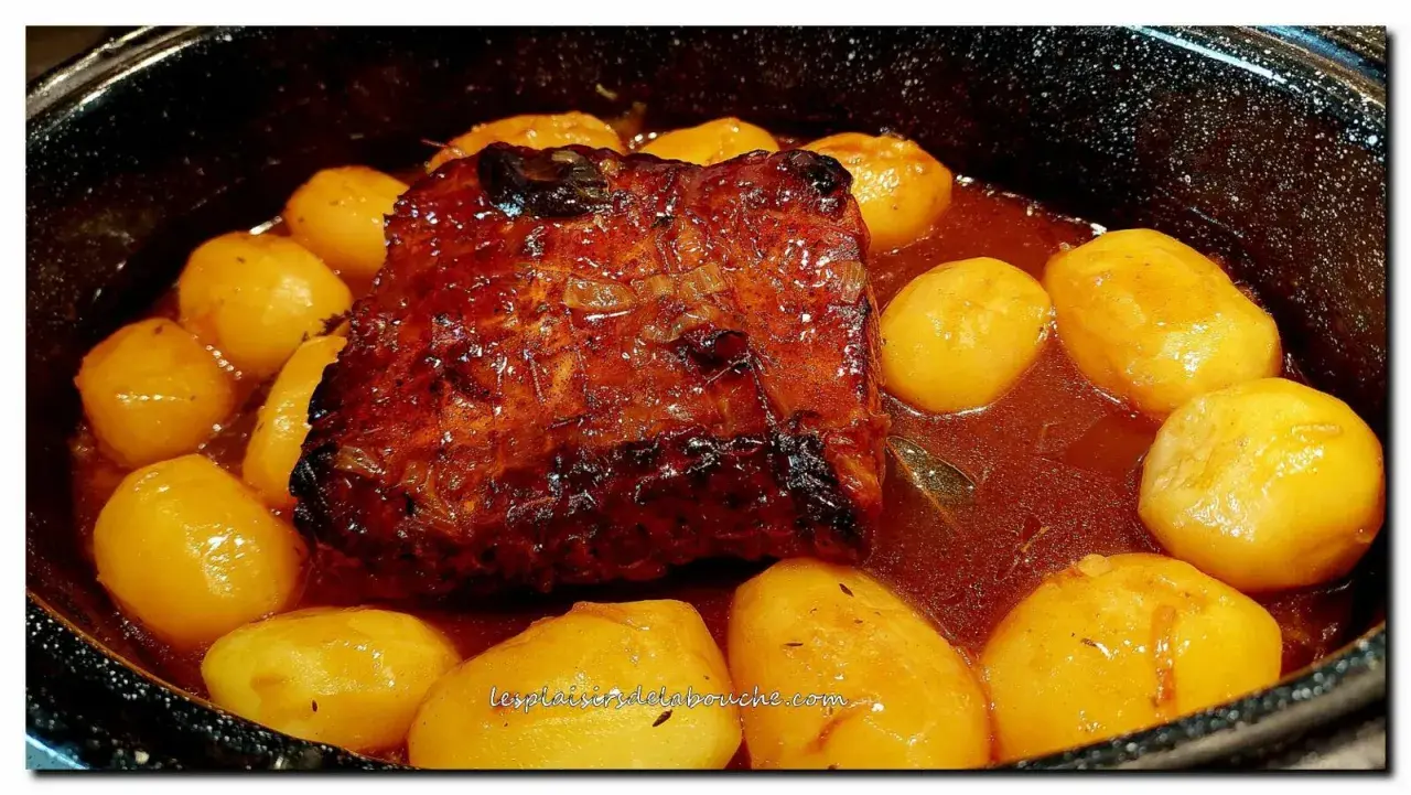 Un rôti de porc à la cocotte en sauce, doré et savoureux, mijote avec des pommes de terre fondantes. Un plat réconfortant prêt à être dégusté.