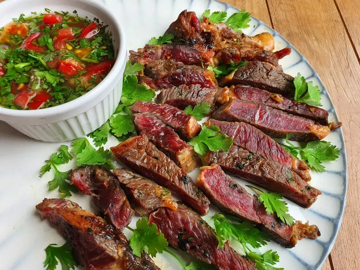 Tranches de bœuf grillé, juteuses et saignantes, servies avec une sauce tomate et coriandre. Un plat qui ferait presque pleurer de joie un tigre gourmand.