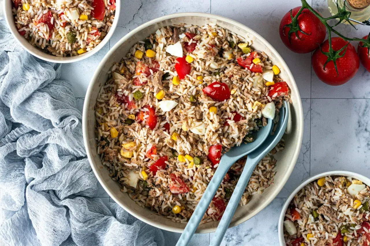 Un grand bol de salade de riz thon, garnie de tomates, maïs et œufs durs. Parfait pour un repas léger et savoureux.