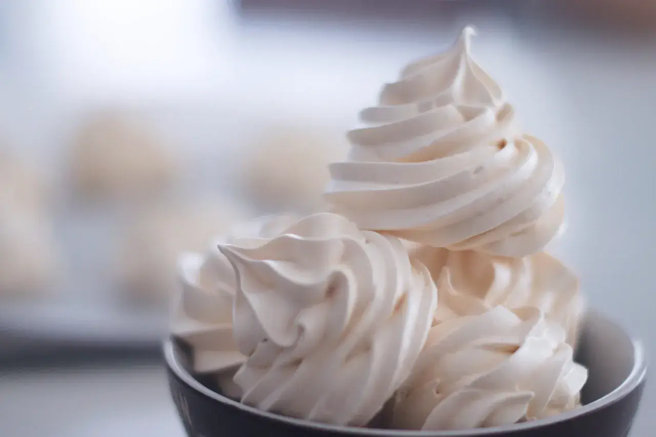 Un bol rempli de délicieuses meringues suisses, légères et aériennes, prêtes à fondre en bouche.