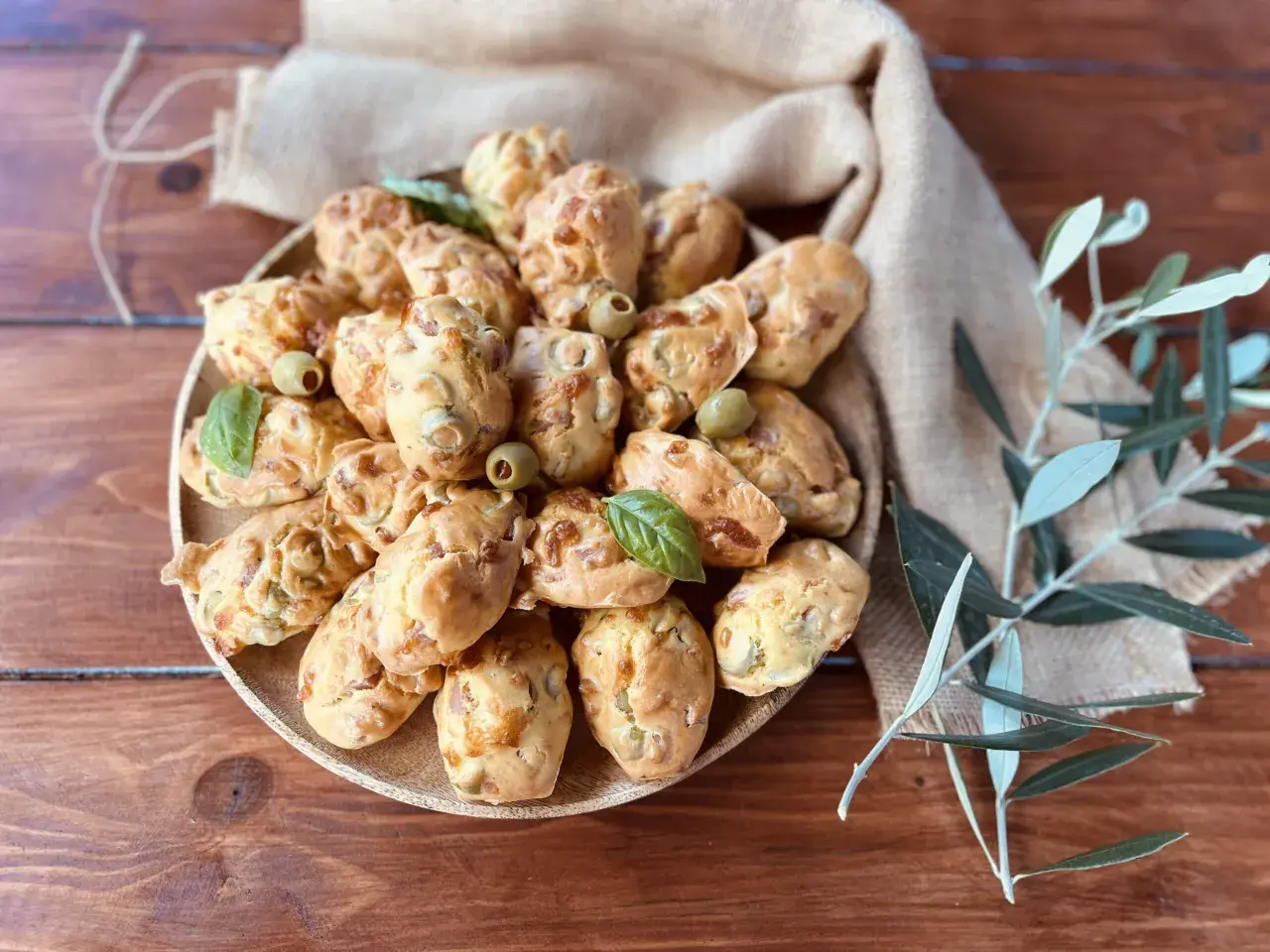 Plate of savory madeleines with olives and basil, perfect for an aperitif.
