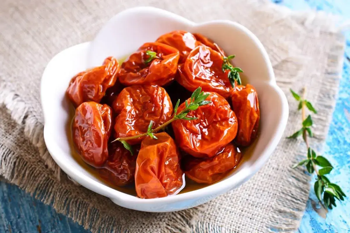 Tomates séchées confites dans de l'huile d'olive, garnies de thym frais. Une recette rapide pour un goût intense.