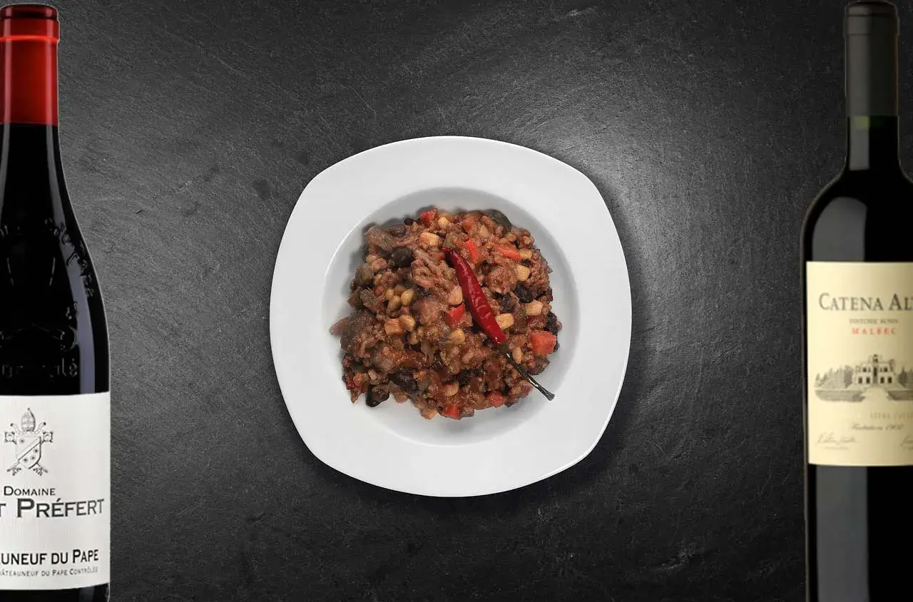 Un plat de chili con carne épicé, accompagné de deux bouteilles de vin rouge. Quel vin avec chili con carne ?