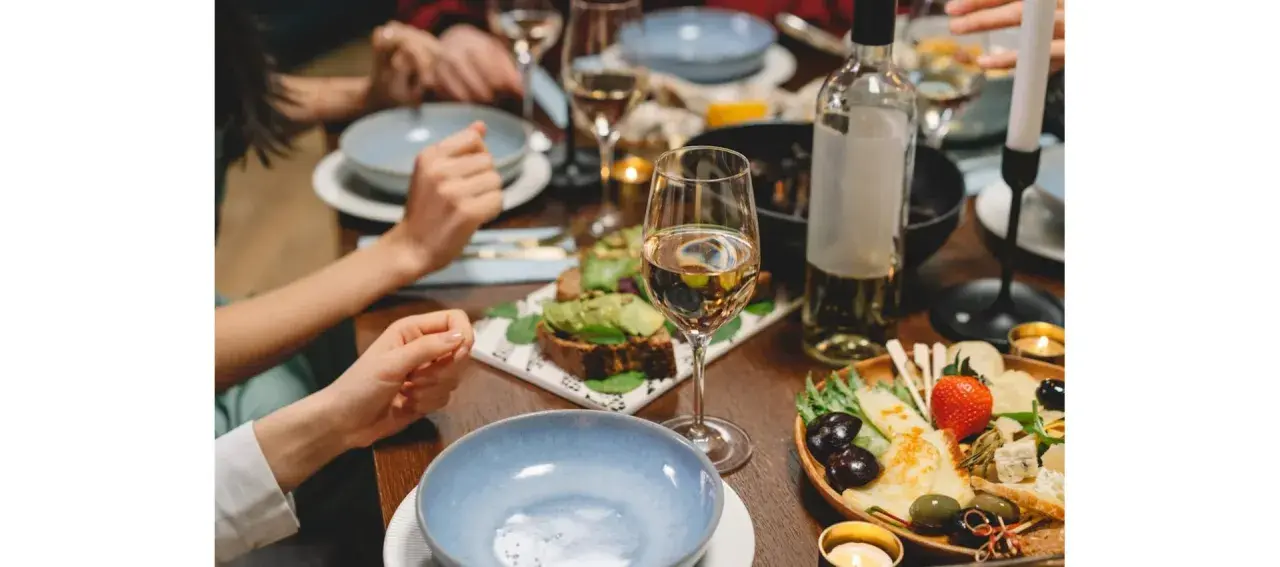 Un verre de Gewurztraminer accompagne un plateau de fromages, olives et fruits, ainsi que des toasts à l'avocat. Un repas convivial.