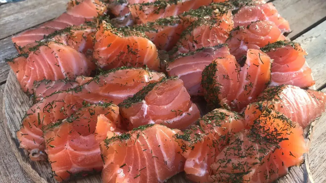 Des morceaux de saumon gravlax, parsemés d'aneth, prêts à être dégustés. Quel vin avec saumon gravlax ? Un blanc sec ou un rosé léger serait parfait.