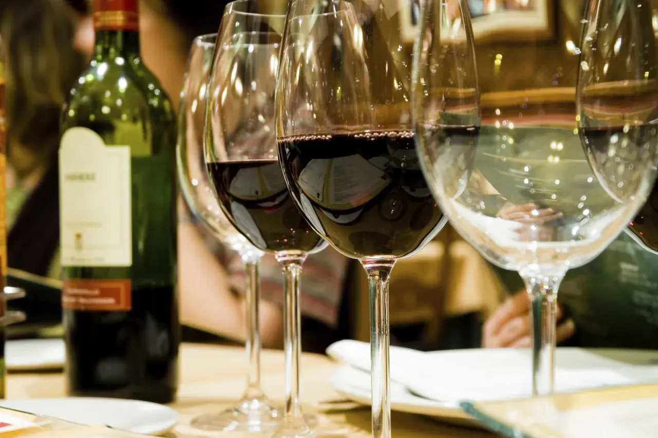 Bouteille de vin vert et verres remplis, révélant la belle couleur du vin rouge profond.