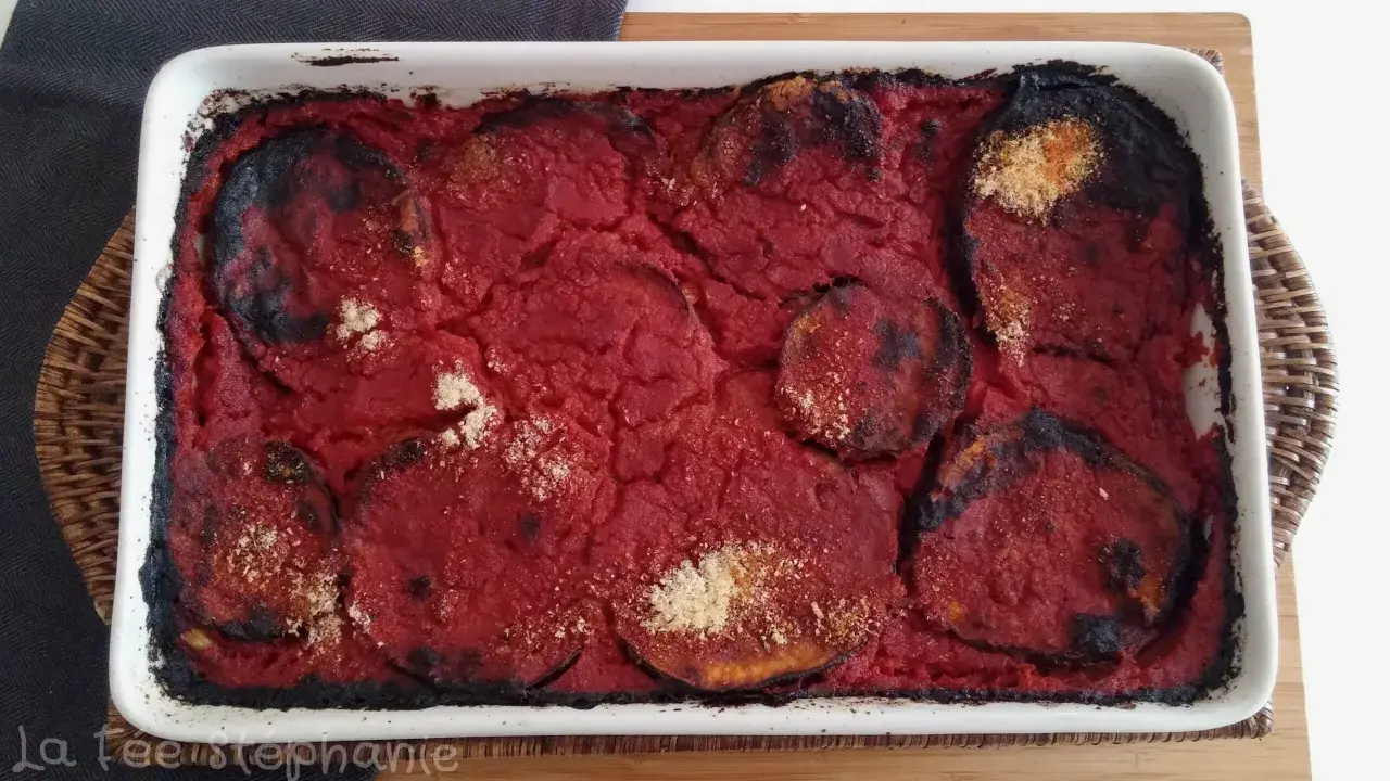Un plat de parmigiana di melanzane tout juste sorti du four, avec des bords légèrement caramélisés et une sauce tomate savoureuse.