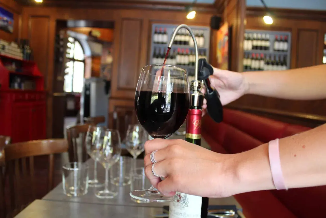 Service d'un vin rouge ouvert avec un tire-bouchon à pompe. La conservation du vin est assurée.