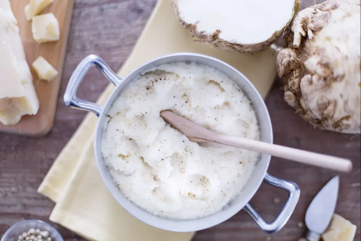 Un crémeux **purée de céleri** dans une casserole, avec du céleri-rave, du parmesan et du poivre.