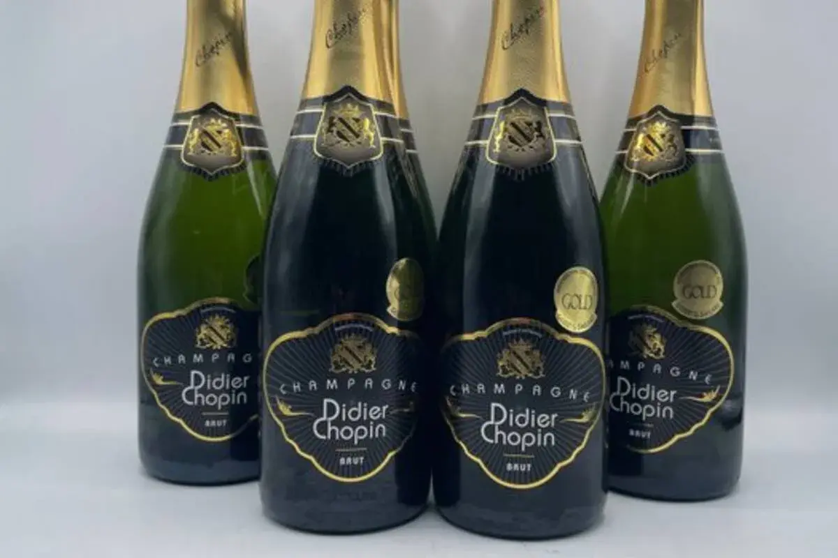 Quatre bouteilles de champagne Didier Chopin Brut, deux en verre sombre et deux en verre vert, avec leurs étiquettes noires et dorées. Un avis sur champagne Didier Chopin.