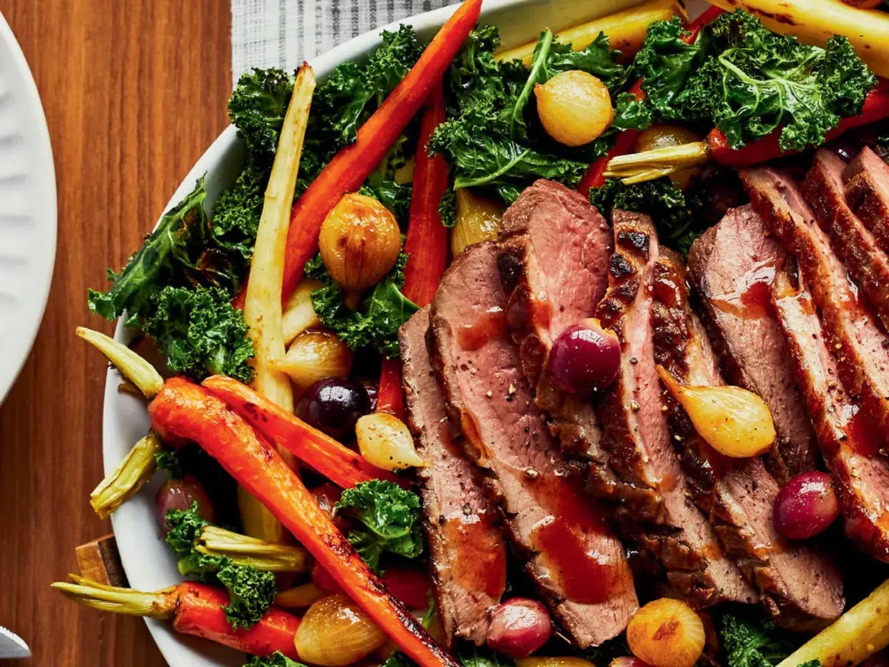 Tranches de magret de canard aux 3 légumes rôtis : carottes, oignons grelots et chou kale. Un plat savoureux et coloré.