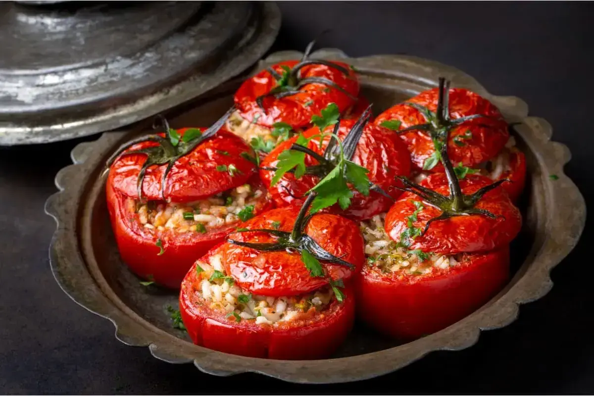 Tomates farcies au riz, garnies de persil frais, servies dans un plat en métal vieilli. Un délice simple et savoureux.
