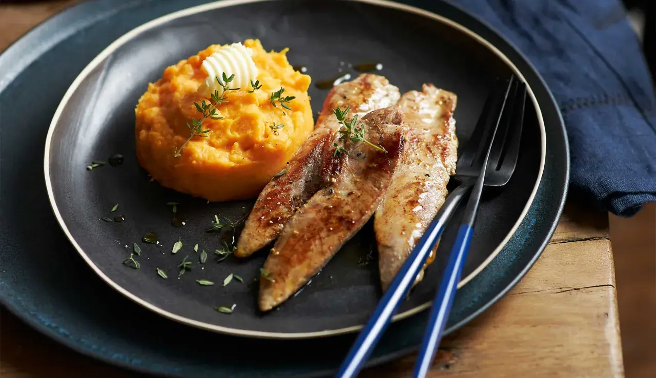 Trois aiguillettes de canard poêlées, servies avec une purée de patate douce onctueuse, garnie de thym frais et d'une noix de beurre.