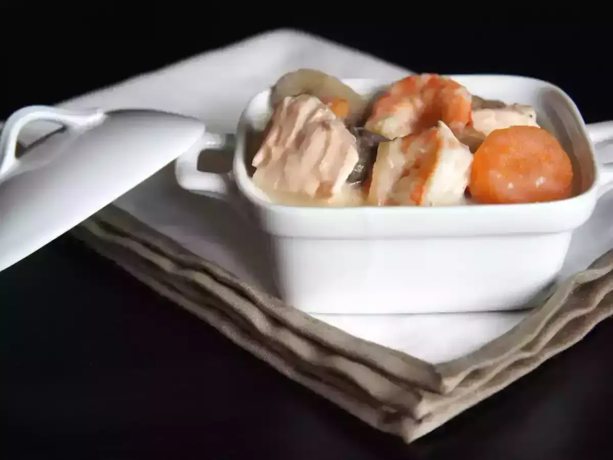 Blanquette de saumon et crevettes, nappée d'une sauce onctueuse au vin blanc, servie dans un ramequin blanc.