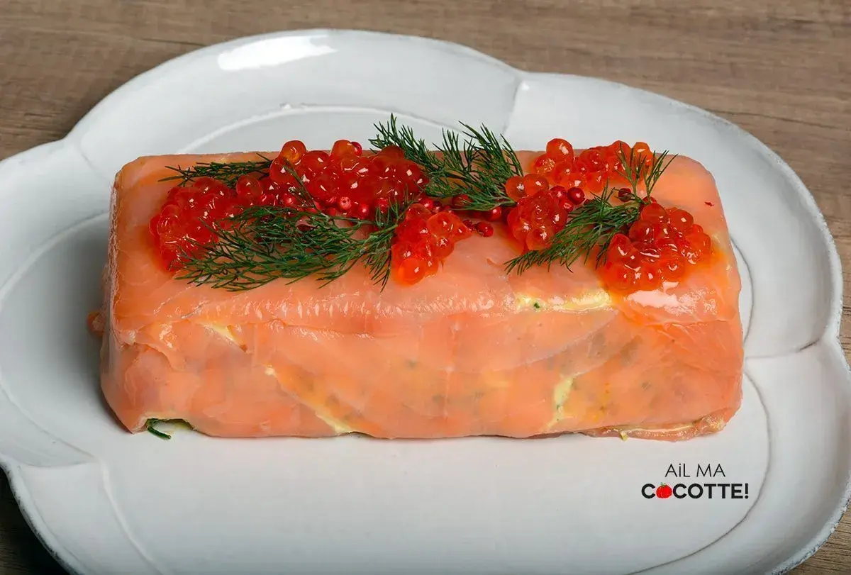 Terrine de saumon chef étoilé, ornée de perles de corail et d'aneth, une création culinaire raffinée.