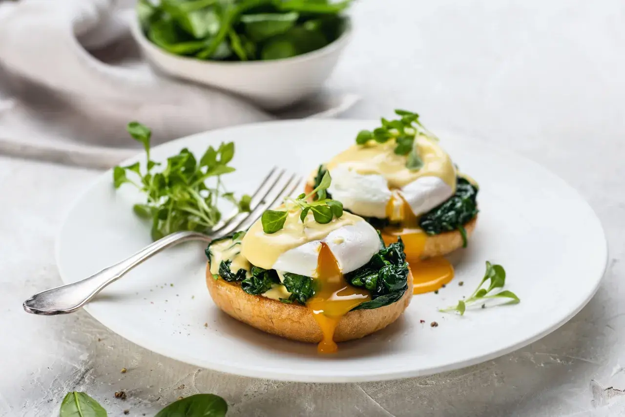 Deux œufs pochés sur des muffins anglais, recouverts de sauce hollandaise et d'épinards. Un déliceux œuf florentin prêt à être dégusté.