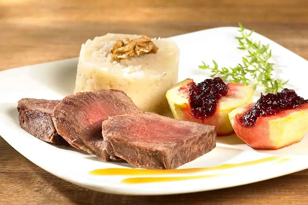 Tranches de fondue de biche, purée de céleri-rave à la noix, quartiers de pêche poêlée au coulis de fruits rouges.