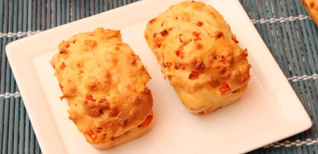 Deux petits pains dorés, un délicieux cake aux légumes, sont servis sur une assiette blanche.