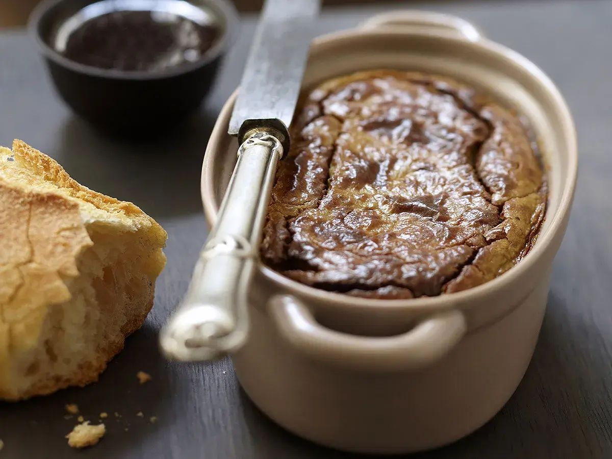Un délicieux gâteau de foie de volaille à l'ancienne, servi avec du pain croustillant et une petite coupelle de confiture.