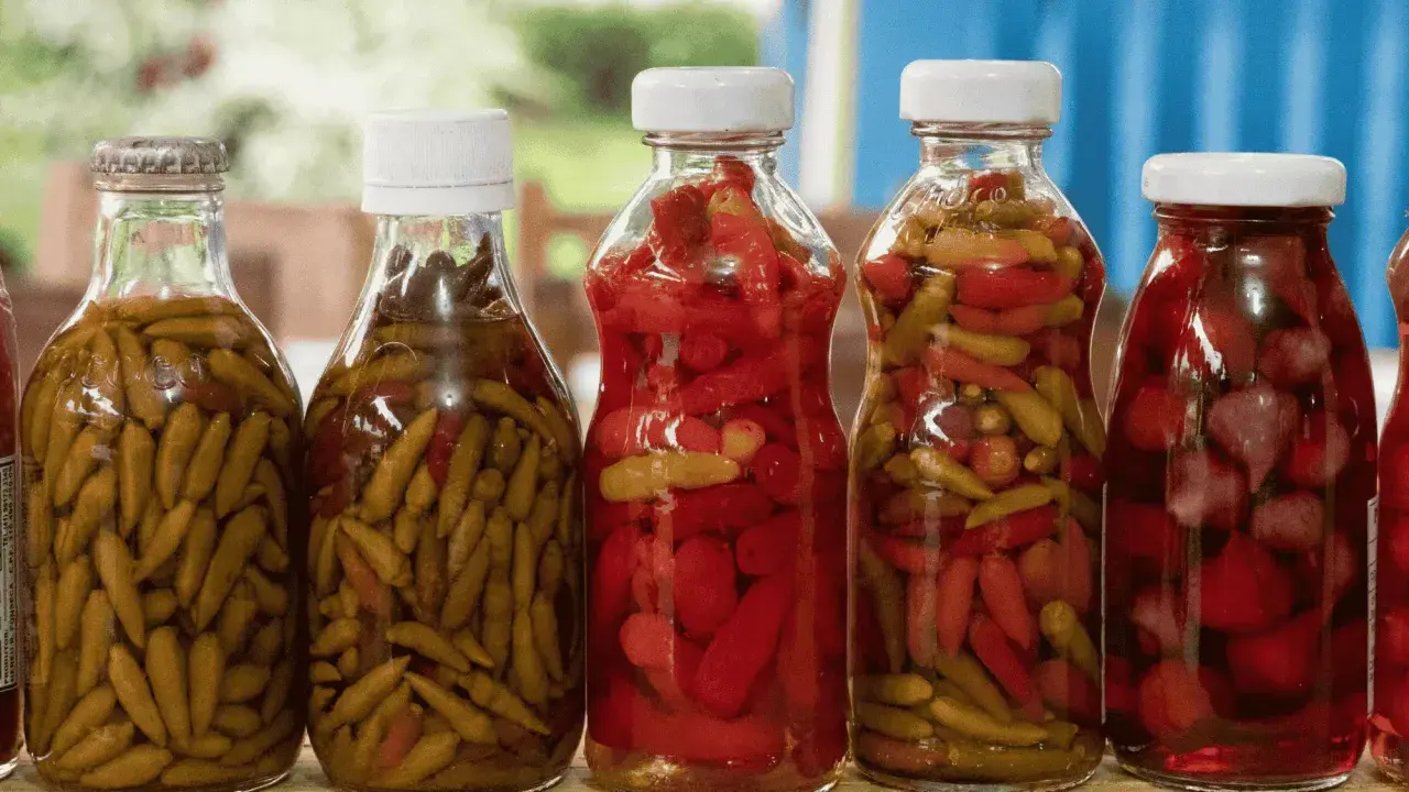 Bouteilles de piments verts et rouges marinés, prêts pour une recette de pickles maison.