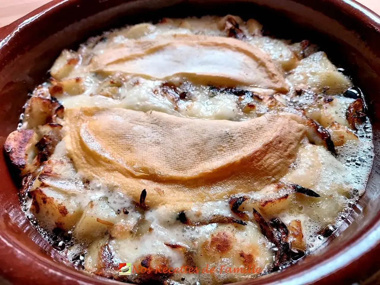 Tartiflette gratinée dans un plat en terre cuite, parfaite avec un vin blanc savoyard. Quel vin pour une tartiflette ?